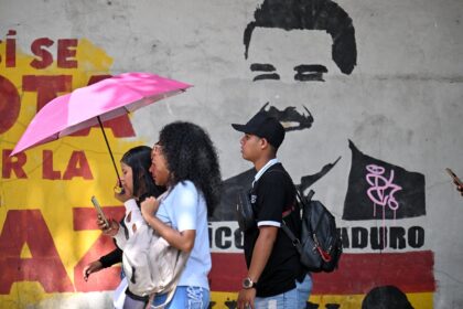 People walk past a mural depicting now ousted Venezuelan president Nicolas Maduro near the