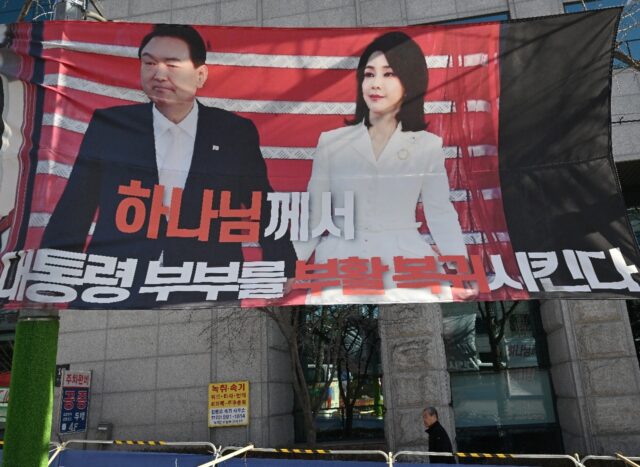 A man walks past a banner showing a picture of South Korea's former impeached preside
