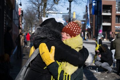 Two women hug at a makeshift memorial in the area where Alex Pretti was shot dead by feder