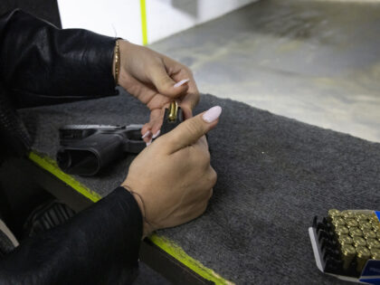A participant loads a magazine with bullets during a training session at a shooting range