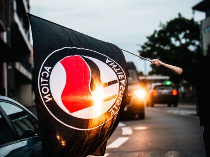 An activist waves a black anti-fascist flag in traffic at nightfall, in Saint-Brieuc, Fran