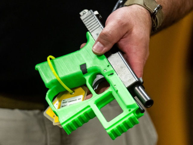 An ATF official holds a 3D printed gun in the National Firearm Reference Vault, which hold