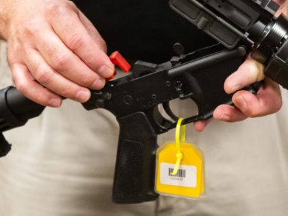 An ATF official installs a red 3D printed gun conversion device that enables a lawful semi