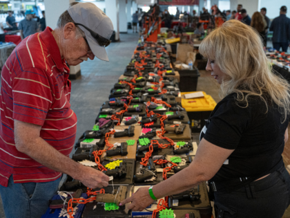 A saleswoman shows weapons to a buyer at her gun booth at the Expo Gun Show in Tucson, Ari