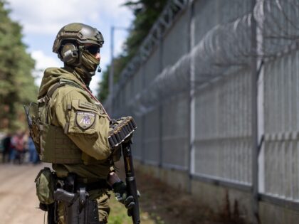 A Polish border guard officer stands at the Polish-Belarusian country border in front of t