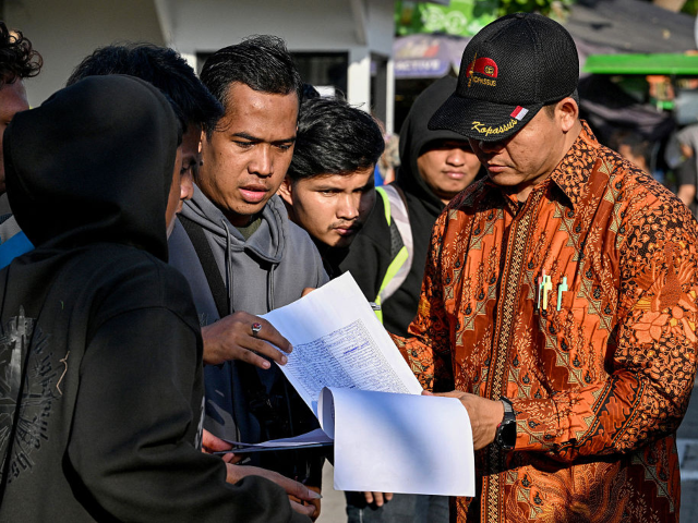 People check their names on a list in front of the Indonesian Embassy in Phnom Penh on Jan