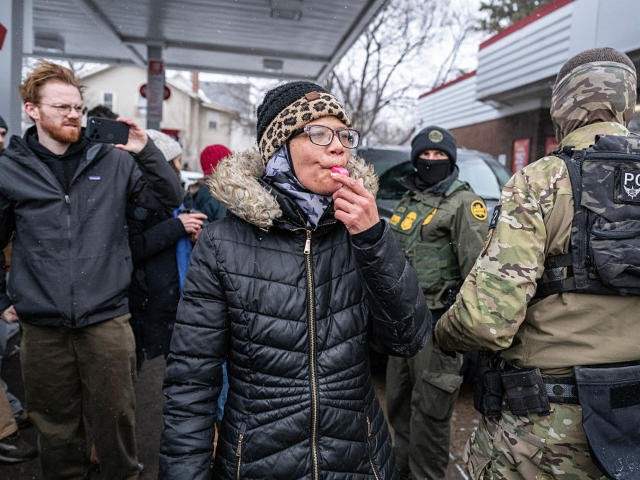 A woman blows her whistle at US Border Patrol agents at a gas station in Minneapolis, Minn