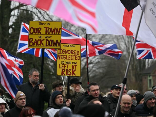 Protesters waving flags and holding placards listen to speakers after taking part in a mar