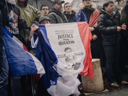 A person in the crowd is holding a French flag that reads Mort pour nos soeurs mort pour l