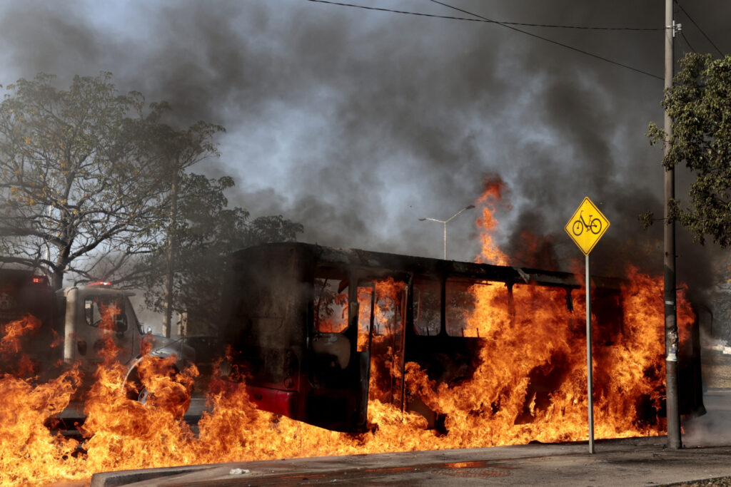 A bus set on fire by organised crime groups in response to an operation in Jalisco to arrest a high-priority security target, burns at one of the main avenues in Zapopan, state of Jalisco, Mexico, on February 22, 2026. Armed civilians blocked several roads in the state of Jalisco, in western Mexico, following an operation by federal forces in the town of Tapalpa, local authorities reported. Jalisco, which will host four matches of the upcoming 2026 World Cup, is home to the powerful Jalisco New Generation Cartel (CJNG), and has been rocked by several episodes of violence in recent years. (Photo by Ulises Ruiz / AFP via Getty Images)