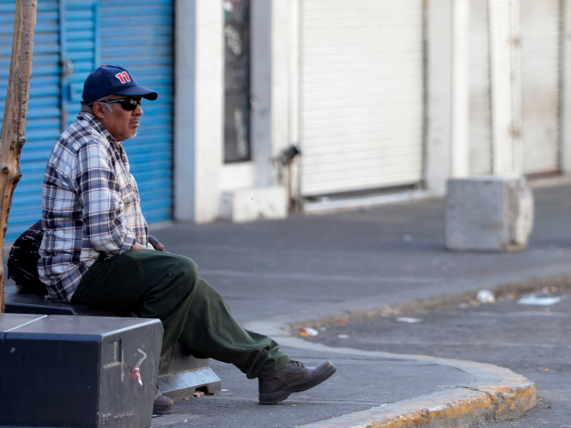 GettyImages-2262730500 A man sits in front of closed shops in the San Juan de Dios commercial district in the his