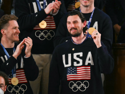 Goalie Connor Hellebuyck raises his gold medal as members of the US Men's Olympic hockey t