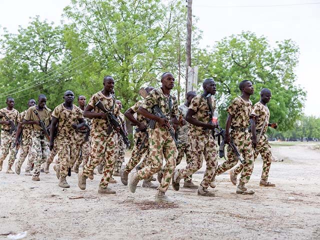 Nigerian soldiers from the Multinational Joint Task Force (MNJTF) run while singing during