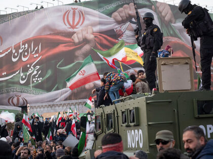 Armed members of Iran's police special forces monitor an area while standing on an armored
