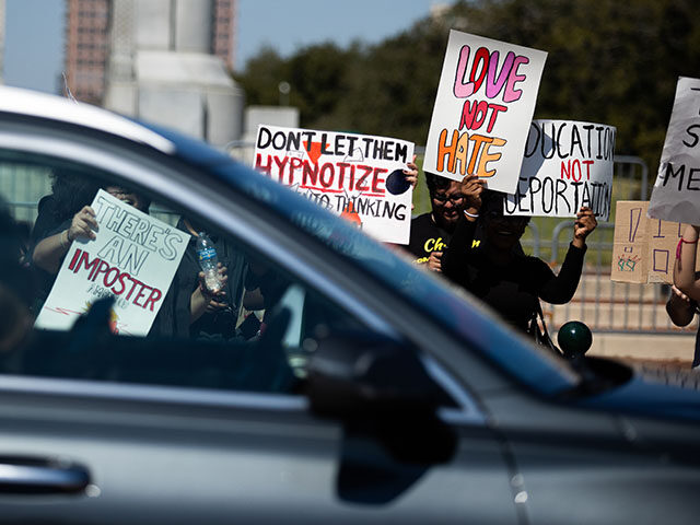 GettyImages2261593602 Protesters hold signs as cars pass by during a student-led demonstration against I.C.E. in