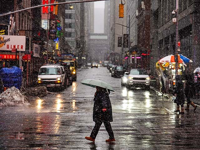 People walk along the street during snowfall on February 22, 2026 in New York City. A majo