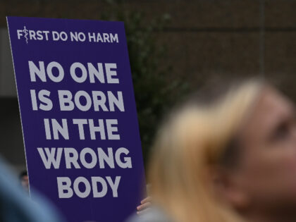 A person holds a placard with words 'No One Is Born In The Wrong Body' as hundre