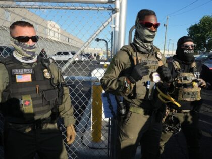 Immigration and Customs Enforcement (ICE) agents stand near a gate at Delaney Hall, a newl