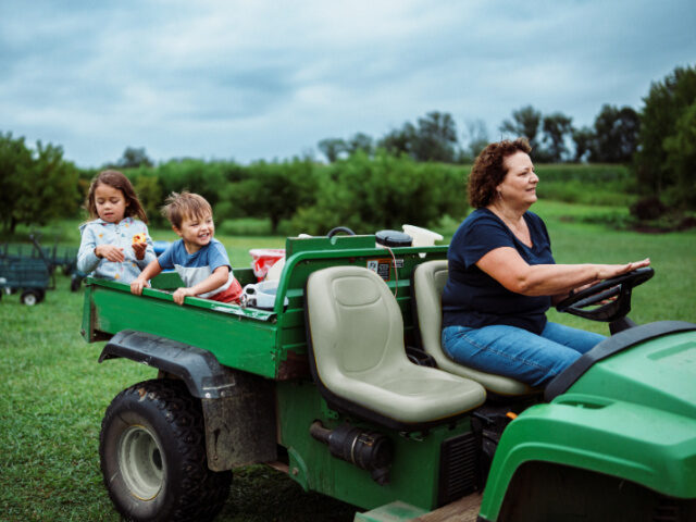 A three-year-old Eurasian boy laughs as he rides in the back of a utility vehicle with his