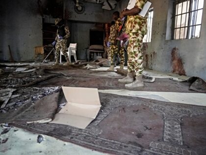 Military personnel inspect the scene of the explosion at a mosque in the Gamboru market in
