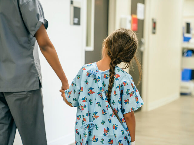 Nurse holding hands with child in hospital - stock photo