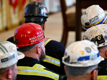 A worker wears a "Make America Great Again" sticker on a hard hat while attendin