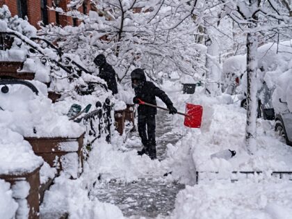 NEW YORK, NEW YORK - FEBRUARY 23: Two men shovel snow as snow blankets streets and limits
