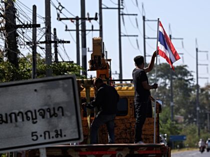 SURIN, THAILAND - DECEMBER 21: A man holds a Thai flag as the convoy carrying the body of