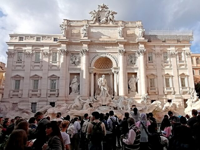 People crowd in the Piazza di Trevi to view the Trevi Fountain, the largest Baroque founta