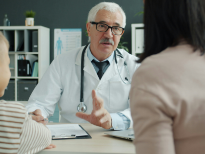 vitaly-gariev-ibZ2QiKkEsg-unsplash Doctor consults with mother and child in office.