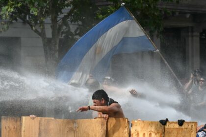 Argentine demonstrators are hit by water cannon fired by riot police during a protest in B