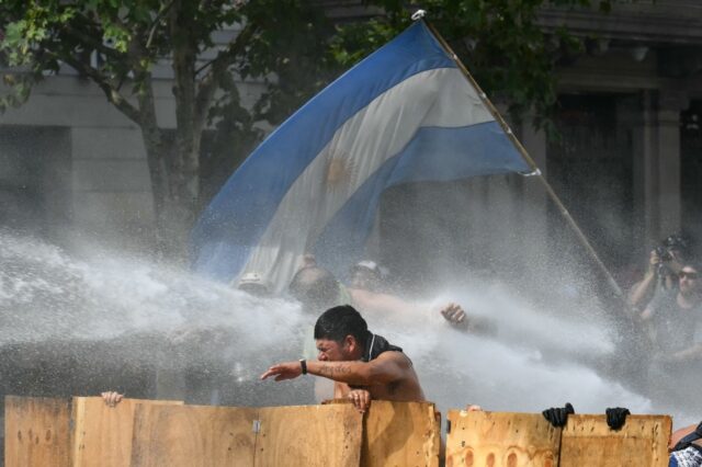 Argentine demonstrators are hit by water cannon fired by riot police during a protest in B