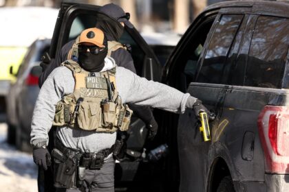 Federal agents stand by a vehicle after they detained a protester in Minneapolis, Minnesot