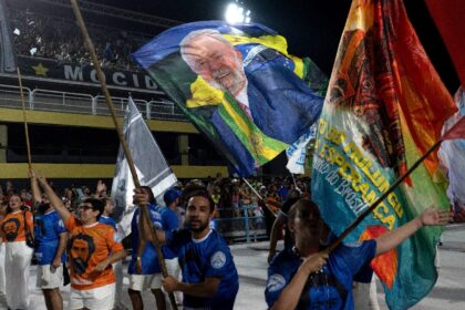 Revelers from the Academicos de Niteroi samba school wave flags depicting Brazil's Pr