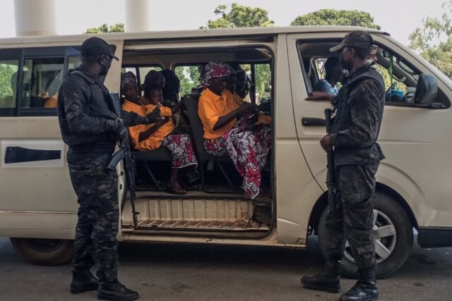 Security officers stand guard next to a bus carrying freed worshippers in northern Nigeria