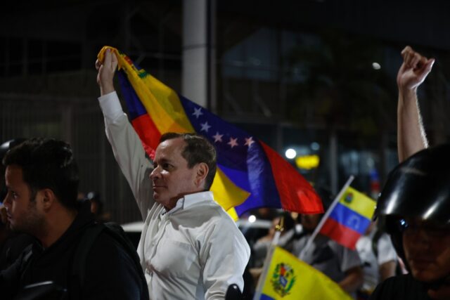Venezuelan opposition politian leader Juan Pablo Guanipa waves a national flag after his r