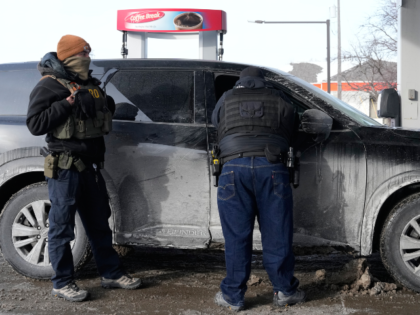 ICE agents stand by their vehicle at a gas station, Monday, Jan. 19, 2026, in St. Paul, Mi