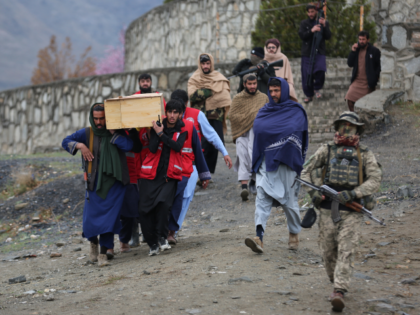 Taliban security personnel guard as people carry the remains of victims of a Monday airstr