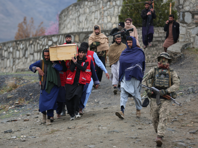 Taliban security personnel guard as people carry the remains of victims of a Monday airstr