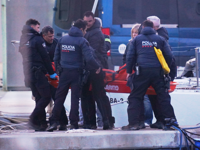 Police officers carry the body of a person found in the waters off the Port of Barcelona,