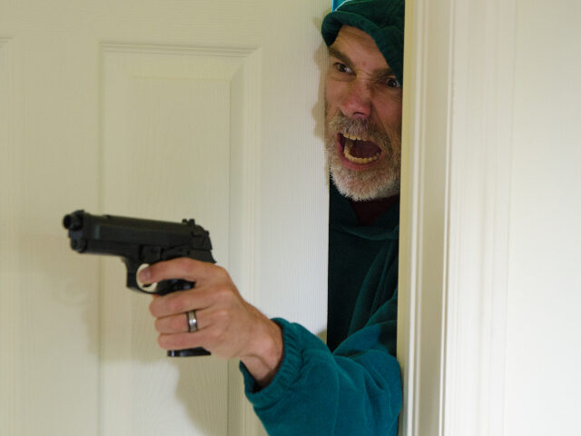 Armed man looking out of bedroom door