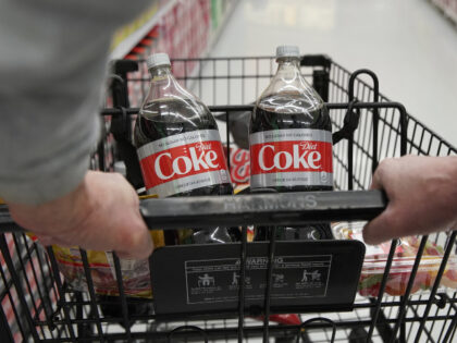 A shopper pushes a cart with two bottles of Coca-Cola Co. Diet Coke soft drinks at a store