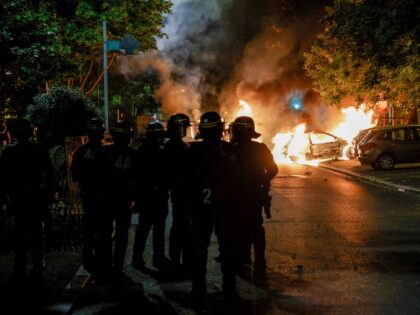 Police officers stand near burning cars during protests in Nanterre, west of Paris, on Jun
