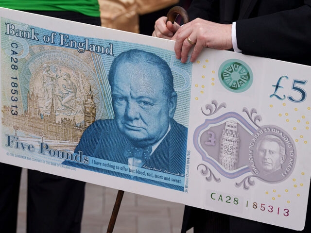 A member of staff from the the Bank of England holds a specimen £5 bank note featuring Si