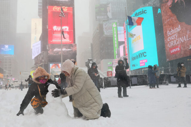 NEW YORK, NEW YORK - FEBRUARY 23: People build a snowman in Times Square amid a blizzard o