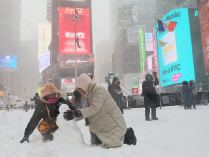 NEW YORK, NEW YORK - FEBRUARY 23: People build a snowman in Times Square amid a blizzard o