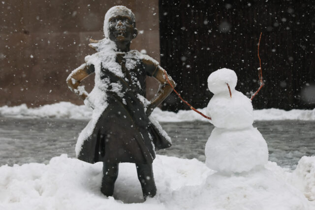 NEW YORK, NEW YORK - FEBRUARY 23: The Fearless Girl statue is seen next to a snowman in fr