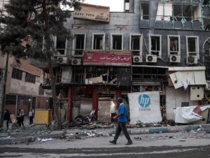 A man walks past damaged residential buildings near Niloufar square in Tehran during the o