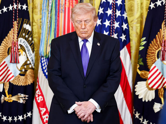 US President Donald Trump bows his head during a medal of honor ceremony in the East Room