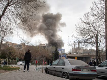 TEHRAN, IRAN - MARCH 2: A person watches as a plume of smoke rises after an explosion on M